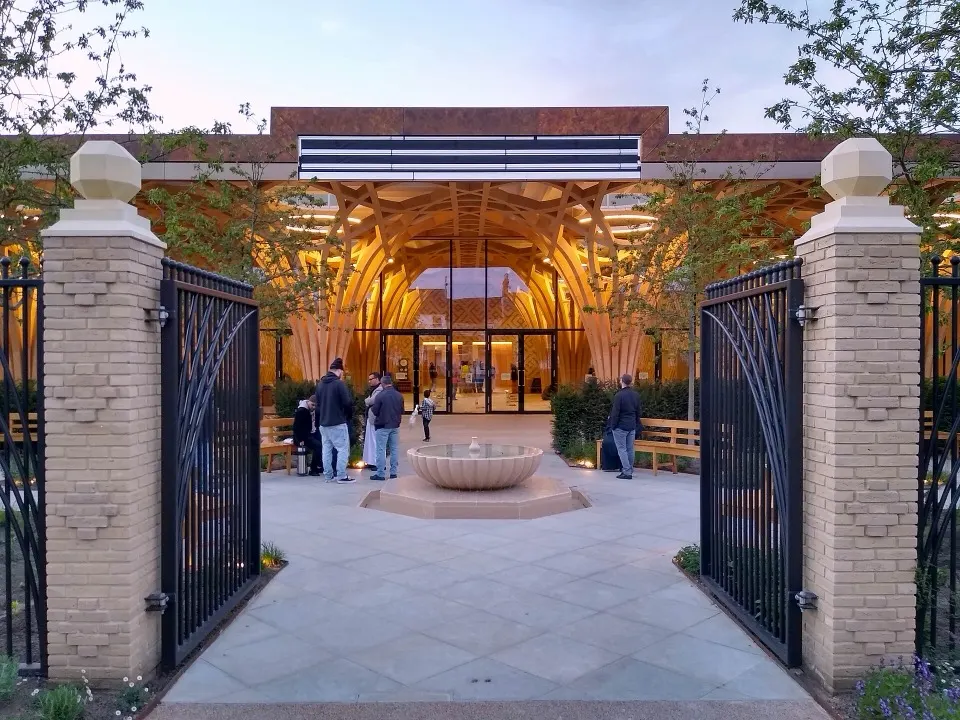 The entrance of Cambridge Central Mosque, timber arches rising behind its garden